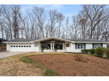 Charming single-story home featuring white brick, a front-facing picture window, and a two-car garage at 665 Lake Charles Way, Roswell, GA 30075