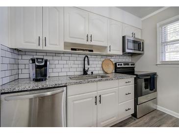 Well-lit kitchen featuring subway tile backsplash, stainless steel appliances, and granite countertops at 6700 Roswell Rd # 32C, Atlanta, GA 30328