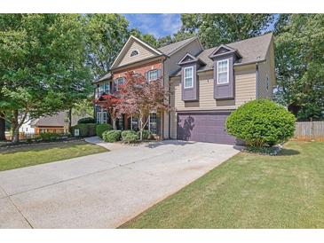 Charming two-story home with a well-manicured lawn, beautiful landscaping, and an attached two-car garage at 2295 Hemrick Rd, Cumming, GA 30041
