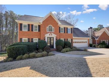 Beautiful two-story brick home with a well-manicured lawn, attached two car garage and mature landscaping at 9470 Dominion Way, Alpharetta, GA 30022