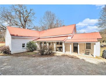 Charming home with a red roof, gravel driveway, and a welcoming covered porch for outdoor relaxation at 204 Emory St, Oxford, GA 30054