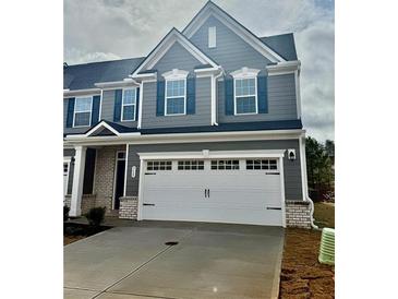 Two-story gray townhome with a two-car garage, gray siding, white trim, and dark blue shutters at 713 Bickmore Dr, Mcdonough, GA 30253