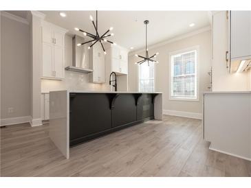 Bright kitchen with modern light fixtures, white cabinetry, and large island with breakfast bar at 275 Briscoe Way # 3, Alpharetta, GA 30009