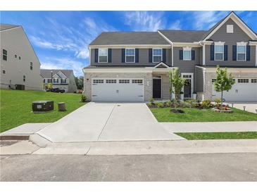 Inviting townhome featuring gray siding, brick accents, a two-car garage, and a well-manicured lawn at 701 Bickmore Dr, Mcdonough, GA 30253