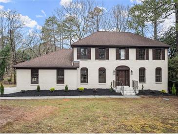 Charming two-story home with brown shutters, light-colored brick, manicured landscaping and a welcoming front entrance at 743 Cedar Sw Trce, Lilburn, GA 30047