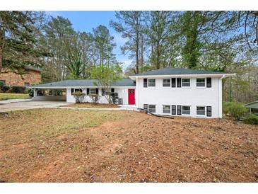 Two-story home featuring white painted brick, black trim, a bright red door, and a covered carport at 3648 Garrison Sw Dr, Atlanta, GA 30331