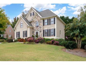 Charming two-story home featuring stone accents and a beautifully landscaped front yard with lush greenery and colorful flowers at 4651 Oakleigh Manor Dr, Powder Springs, GA 30127