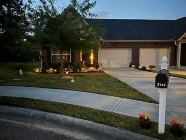 Charming home exterior featuring a lush lawn, a two-car garage, and a well-lit driveway and walkway at 2147 Red Oak Cir, Union City, GA 30291