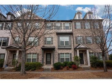 Charming brick townhome with symmetrical windows, shutters, manicured bushes, and lush trees at 1430 Baygreen Rd, Suwanee, GA 30024