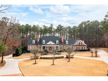 Stately brick home featuring a circular driveway and well-manicured landscaping and covered front porch at 3201 Hobsons Ridge Nw Trl, Acworth, GA 30101