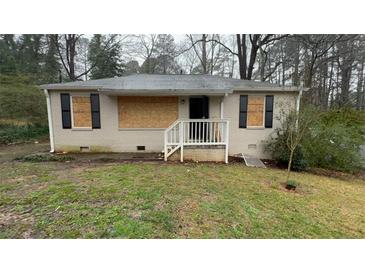Exterior of a one-story home featuring a brick facade, black shutters, and boarded-up windows at 1963 Oak Valley Rd, Decatur, GA 30035
