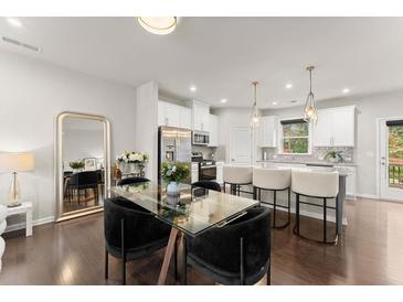 Open concept kitchen and dining space with a large island, modern lighting, and hardwood floors at 2452 Coosa Vly, Atlanta, GA 30339