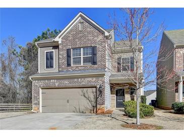 Charming two-story home featuring a brick facade, attached garage, and manicured lawn at 1676 Charcoal Ives Rd, Lawrenceville, GA 30045