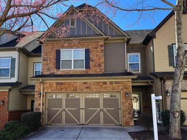 Charming two-story townhome featuring a two-car garage and stone and siding exterior at 2613 Stonekey Bnd, Lithonia, GA 30058