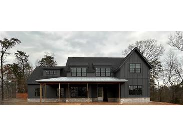 Modern farmhouse-style home with board and batten siding, stone accents, and a welcoming covered front porch at 157 Palisade Dr, Rydal, GA 30171