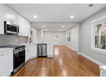 Bright kitchen features stainless appliances, white cabinets, and hardwood floors in an open floor plan at 207 Garrison Se Rd, Marietta, GA 30008