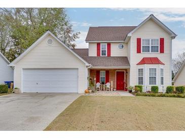 Charming two-story home featuring red accents, a well-manicured lawn, and a two-car garage at 5555 Sugar Crossing Dr, Sugar Hill, GA 30518