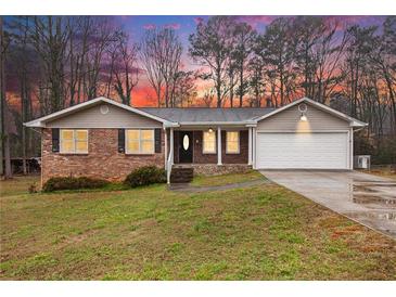 Charming single-story home with brick accents, siding, attached garage, and a well-maintained lawn at 4446 Frontier Way, Sugar Hill, GA 30518