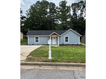 Charming single-story home with light blue siding, black roof, manicured lawn, and inviting front entrance at 6066 Creekford Dr, Lithonia, GA 30058