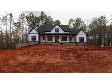 Stunning white farmhouse with black trim, complemented by a dark roof and a spacious, unfinished yard at 472 Price Rd, Carrollton, GA 30116