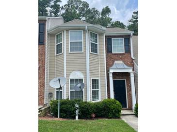 Two-story townhouse with a combination of brick and beige siding with trimmed windows and manicured landscaping at 8170 Oakley Cir, Union City, GA 30291