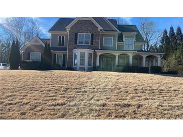 Two-story home with brick and siding, bay window, covered porch, and a well-manicured lawn at 135 Waterlace Way, Fayetteville, GA 30215