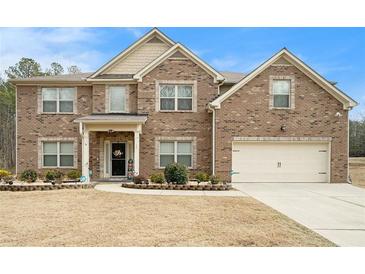 Charming two-story brick home featuring a manicured lawn and attached two-car garage at 10 Tabor Trce, Oxford, GA 30054