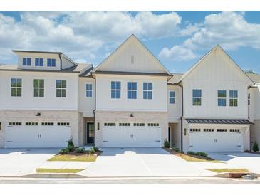 New townhome exteriors featuring white siding, brick accents, and individual one-car garages at 2407 Malster Ln, Lawrenceville, GA 30043
