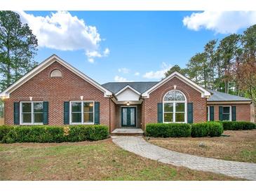 Charming brick home featuring lush landscaping, a well-manicured lawn, and a welcoming walkway to the front door at 2705 Luke Edwards Rd, Dacula, GA 30019