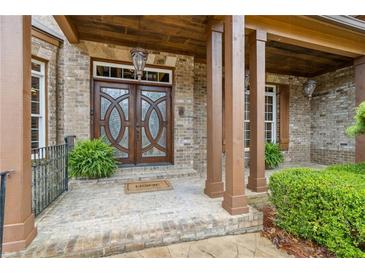 Elegant brick home entrance with custom wood doors and covered porch offers charming curb appeal at 2353 Habersham Sw Dr, Marietta, GA 30064