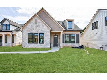 Charming single-Gathering home with stone facade, well-manicured lawn, and inviting entrance at 158 South Village Ave, Holly Springs, GA 30115