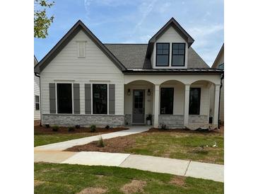 Charming single-Gathering home featuring white siding, stone accents, and a welcoming front porch with elegant columns at 160 South Village Ave, Holly Springs, GA 30115