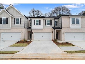 Charming townhome featuring a neutral color palette, two-car garage, and manicured front yard at 324 Shine Dr, Stockbridge, GA 30281
