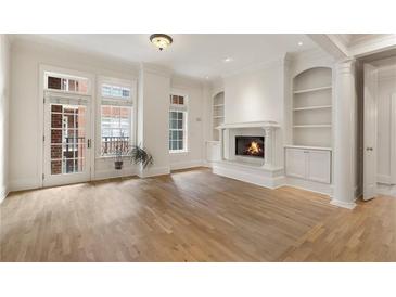 Bright living room with a fireplace, hardwood floors, and large windows leading to a small balcony at 77 Peachtree Ne Pl # 402, Atlanta, GA 30309