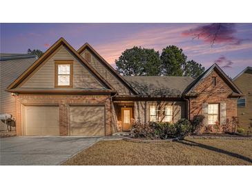 Charming brick home featuring a two-car garage and a neatly maintained front yard with mature landscaping at 1115 Harvest Brook Ne Way, Lawrenceville, GA 30043