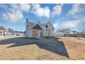 The backyard features a spacious lawn, with an exterior view of the two-story home under a bright, cloudy sky at 3060 White Oak Mews, Decatur, GA 30034