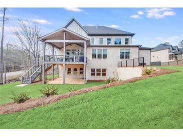 Expansive brick home with covered patio, outdoor stairs, and professionally landscaped yard at 603 Old Peachtree Ne Rd, Lawrenceville, GA 30043