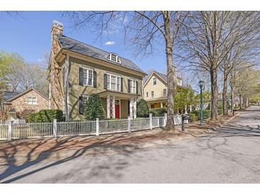 Charming two-story home with a stone chimney, red door, white picket fence, and well-manicured landscaping at 1421 Hedgewood Nw Ln, Kennesaw, GA 30152