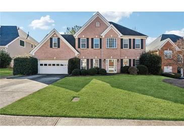 Beautiful brick two-story home featuring a lush green lawn, two-car garage, and mature landscaping at 1470 Oglethorpe Run Ln, Suwanee, GA 30024