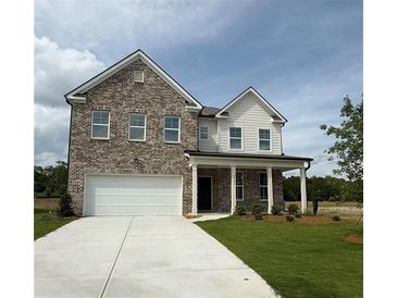 Charming two-story home featuring a classic brick facade, inviting front porch and attached two car garage at 1847 Kingsmere Run Dr, Loganville, GA 30052