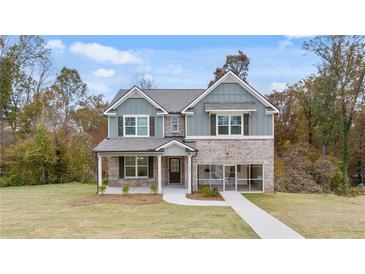 Beautiful two-story home with gray siding, brick accents, well-manicured lawn and cozy screened in porch at 1857 Kingsmere Run Dr, Loganville, GA 30052