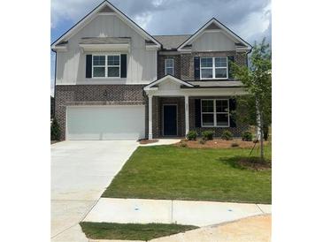 Two-story home with brick facade, a two-car garage, and well-manicured lawn at 1857 Kingsmere Run Dr, Loganville, GA 30052