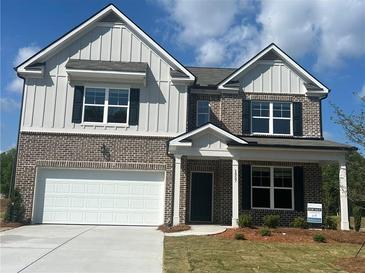 Charming two-story home featuring a brick and board-and-batten facade, black shutters, and a two-car garage at 1857 Kingsmere Run Dr, Loganville, GA 30052