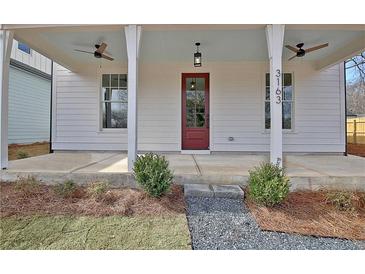 Inviting front porch featuring a red door, ceiling fans and crisp, white columns at 3163 Old Jonesboro Rd, Hapeville, GA 30354