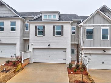 Charming townhome featuring white brick, grey siding, a one-car garage, and well-maintained landscaping at 1317 Fern Ridge Ct # 26, Norcross, GA 30093