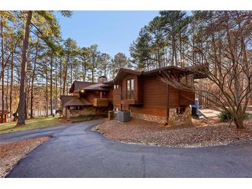 Stunning home boasts wood siding, stone accents, and a picturesque driveway lined with mature trees and lake views at 2513 Overlake Ln, Stockbridge, GA 30281