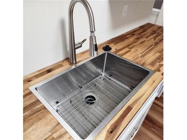 A modern kitchen sink features a stainless steel basin and a stylish faucet set against a wooden countertop at 2413 Charleston Pointe Ct, Atlanta, GA 30316