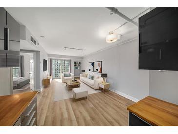 Bright living room featuring hardwood floors, neutral paint, and sliding glass doors to balcony at 199 14Th Ne St # 2407, Atlanta, GA 30309