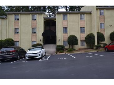 The exterior of this tan two-story condominium building features a dark awning and visitor parking at 2398 Lawrenceville Hwy # K, Decatur, GA 30033