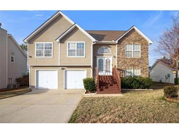 Inviting two-story home with stone accents, a two-car garage, and a well-maintained front lawn at 521 Carlsbad Cv, Stockbridge, GA 30281